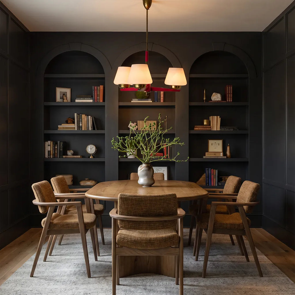 3 light chandeliers centered above a dining table in a dark built-in cabinet dining room.