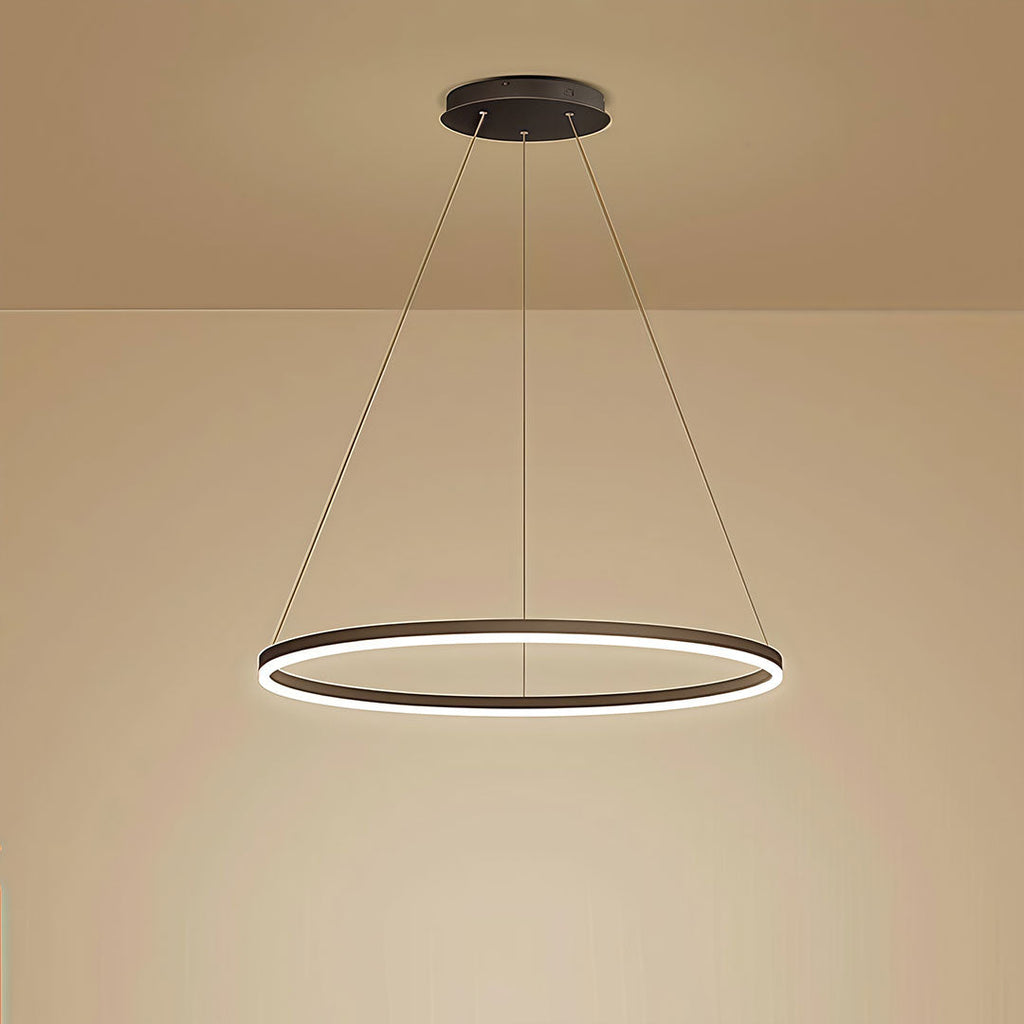 Single black LED ring chandelier glowing with warm light against a beige wall in a dining room.
