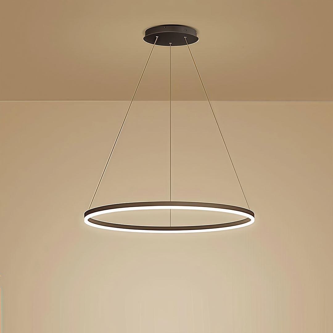 Single black LED ring chandelier glowing with warm light against a beige wall in a dining room.