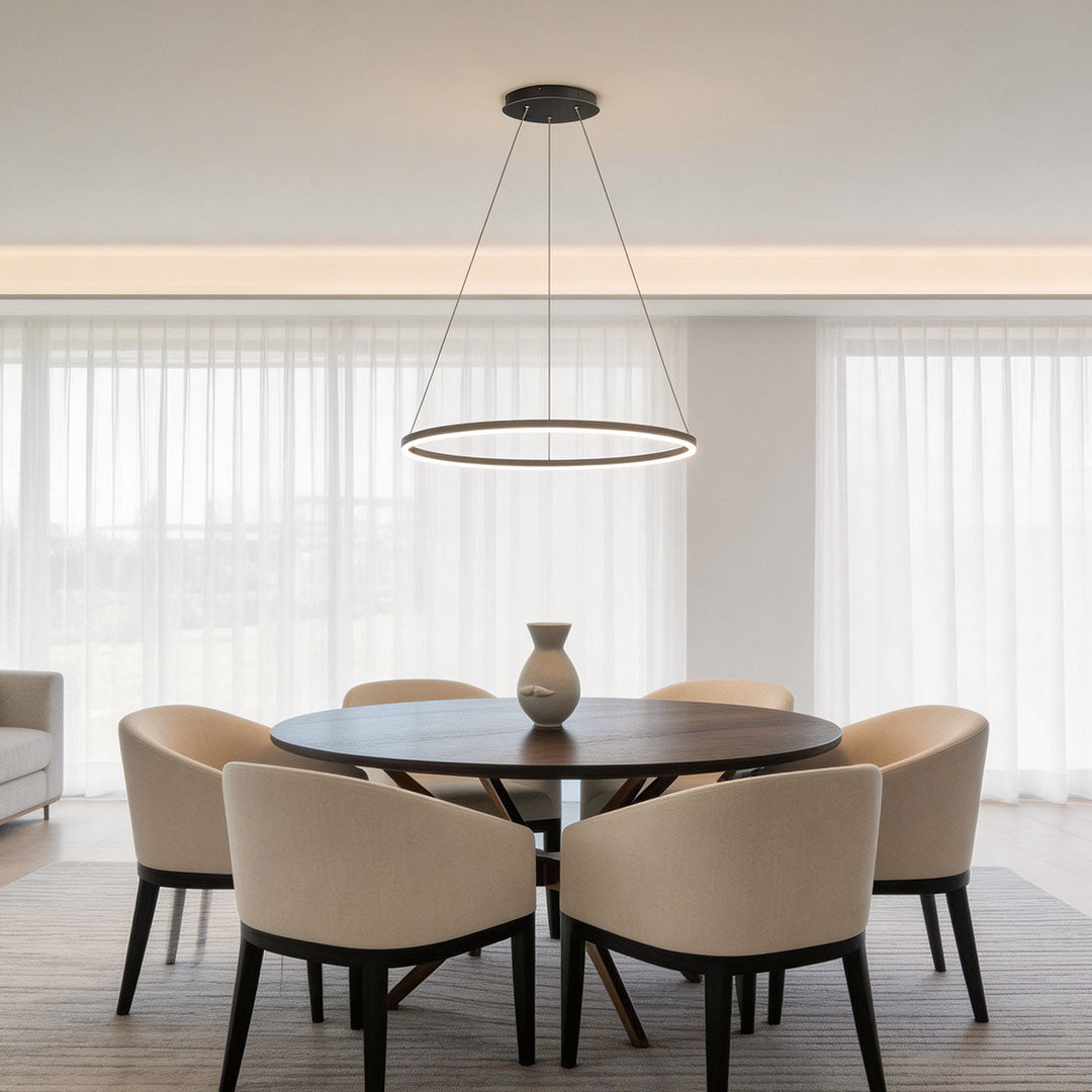 Circular black LED ring chandelier suspended over a round wooden dining table in a bright room.