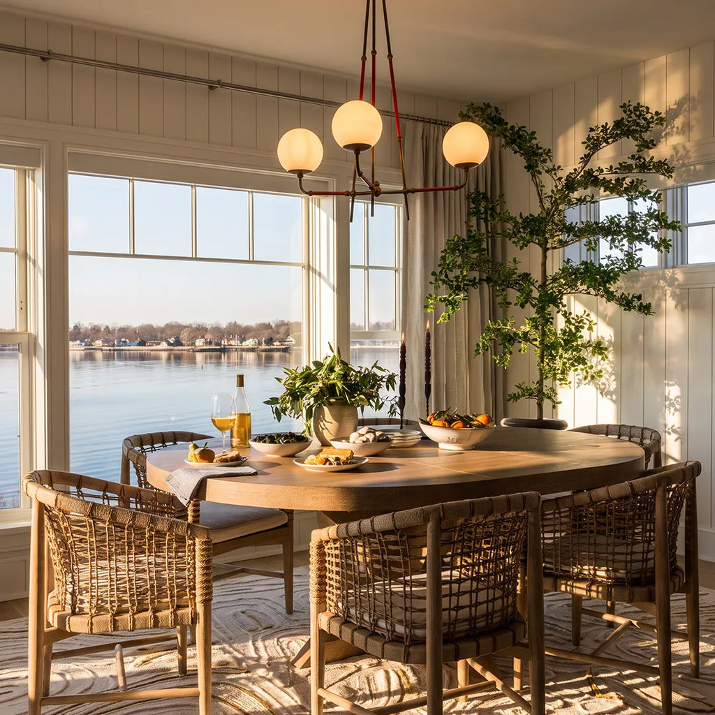 Mid century modern chandelier displayed above a dining table in a bright breakfast room with water views.
