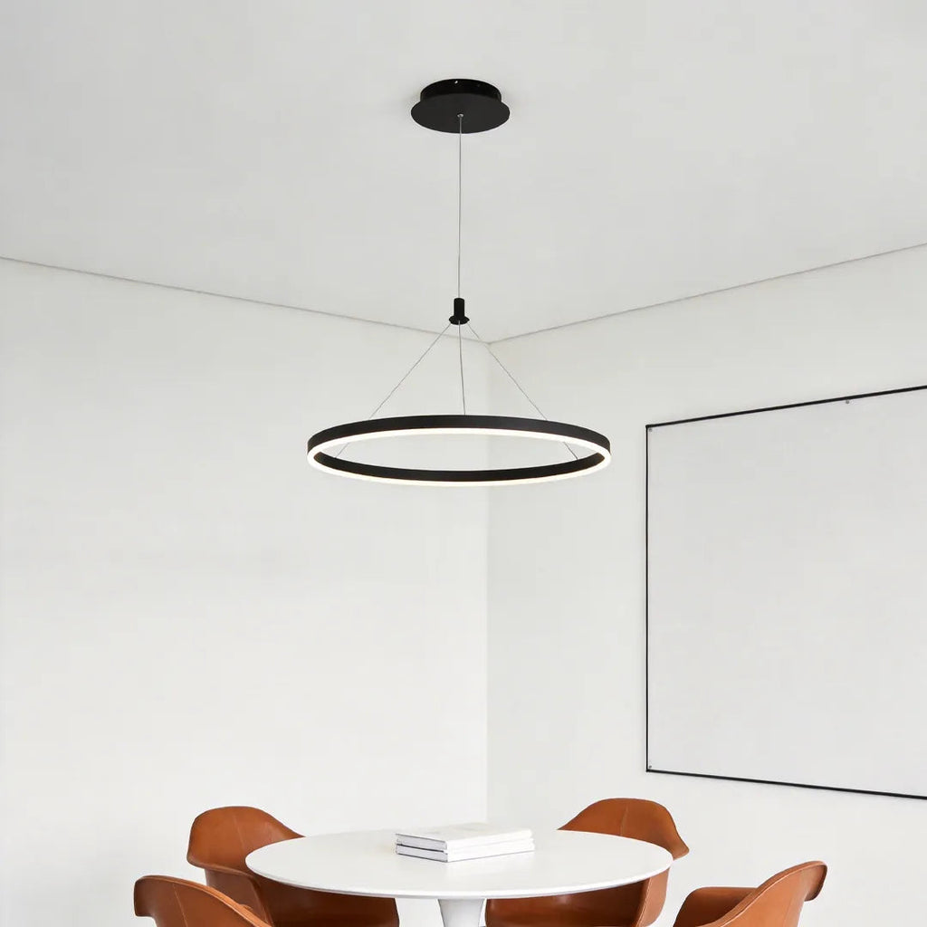 Ring metal chandelier suspended above a round dining table in a clean modern dining space with white walls.
